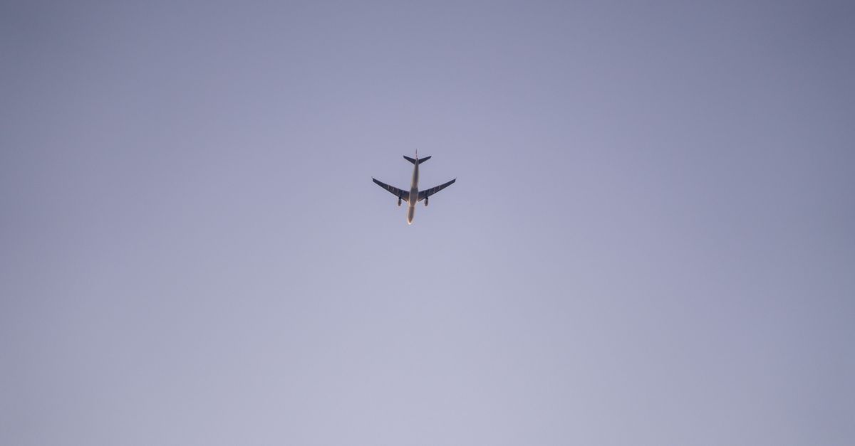 A passenger airplane flying high above, captured against a clear blue sky, showcasing aviation beauty.